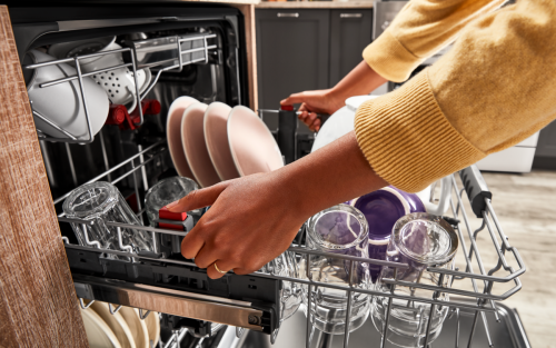 Person pulling out a full dishwasher rack