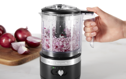 User holding the handle of a food processor chopping onions.