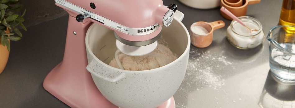 How Does Pretzel Dough Stand Out A pink KitchenAid Stand Mixer is at work, mixing ingredients like flour and sugar, with measuring cups arranged nearby.