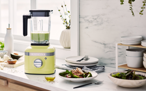 A green KitchenAid® blender with limes and a chicken salad nearby.