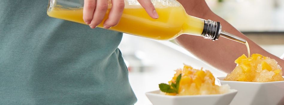 Do Shaved Ice and Crushed Ice Have Different Flavours A person is seen drizzling orange fruit juice into two dishes filled with shaved ice.