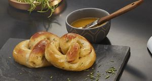 Perfectly browned pretzels served with melted butter for brushing generously over them.