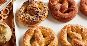 Une variété de bretzels tendres est présentée de manière élégante sur un plat de service blanc.