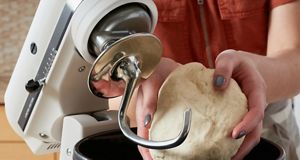  Gentle hands extract a ball of kneaded dough from the KitchenAid Stand Mixer.