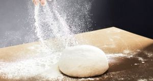  A generous amount of flour is sprinkled onto a large dough ball.