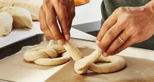 With precision, hands carefully mold the soft dough into pretzel shapes.