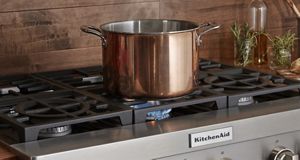 A large metal pot is placed atop a KitchenAid gas stove.