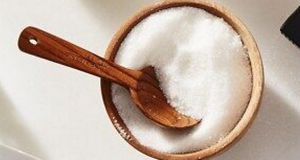 An image capturing coarse salt in a dish, accompanied by a spoon.