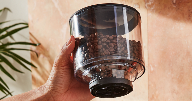 Man holding a canister of coffee beans, prepared to brew.