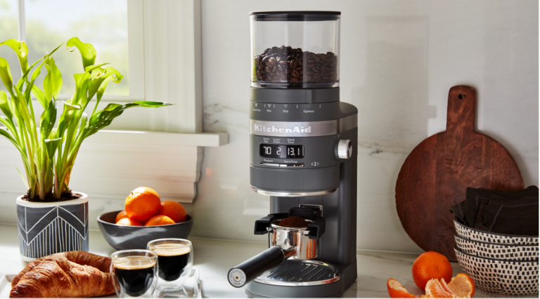 ray KitchenAid coffee grinder surrounded by assorted fruits and baked goods
